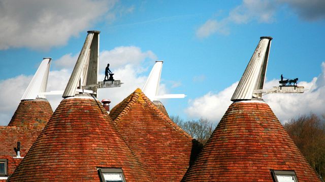 Oast house roofs with wind vanes decorated with agricultural scenes on a farm in Kent