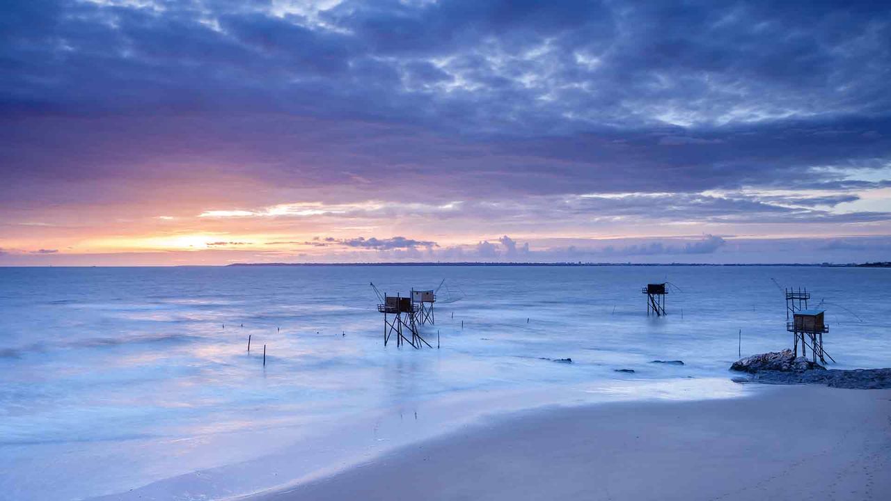 Pêcheries devant un coucher de soleil, France. 