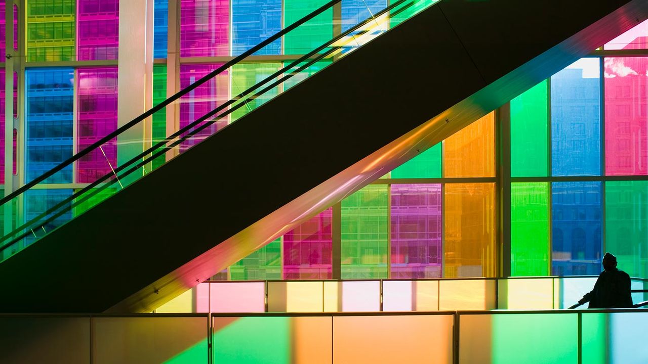 Silhouetted man standing in front of multicolored glass windows of Montreals Palais des Congres Montreal, Quebec, Canada