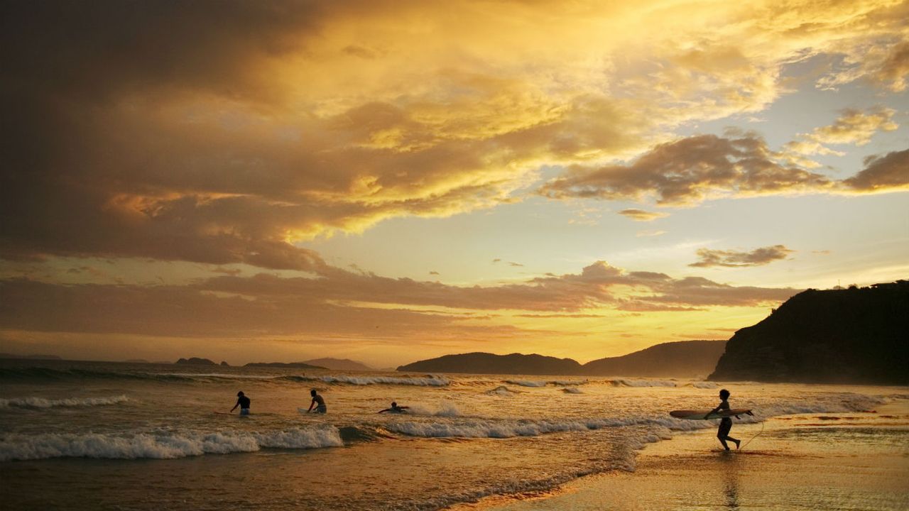 Surfeurs au crépuscule sur la plage de Geriba, Armação dos Búzios, Brésil