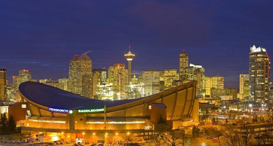 The Saddledome with Calgary Tower and the city skyline in the background at dusk, Calgary, Alberta
