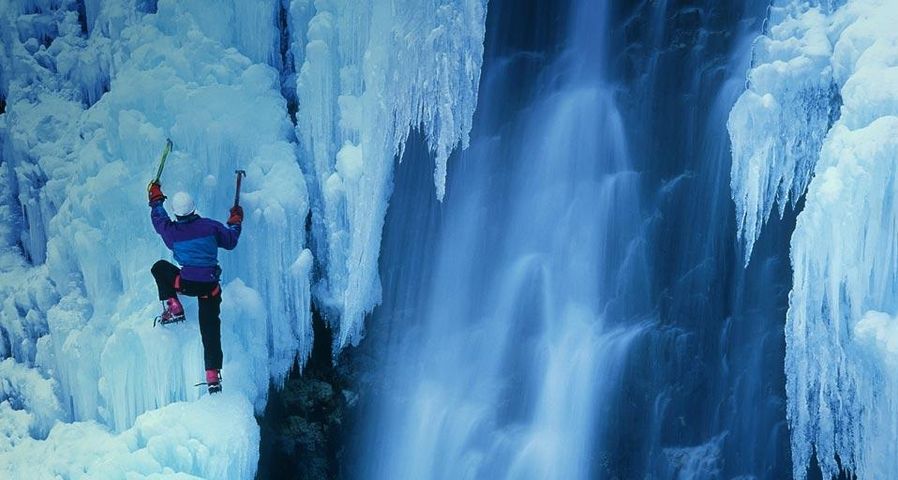 Ice climber ascending a frozen waterfall in Telluride, Colorado