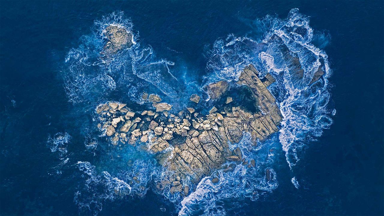 Meereswellen brechen sich an einer herzförmigen Felseninsel vor der Küste von Sydney, Australien