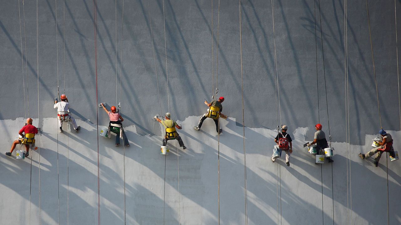 Workers applying stucco to a wall of a new building 