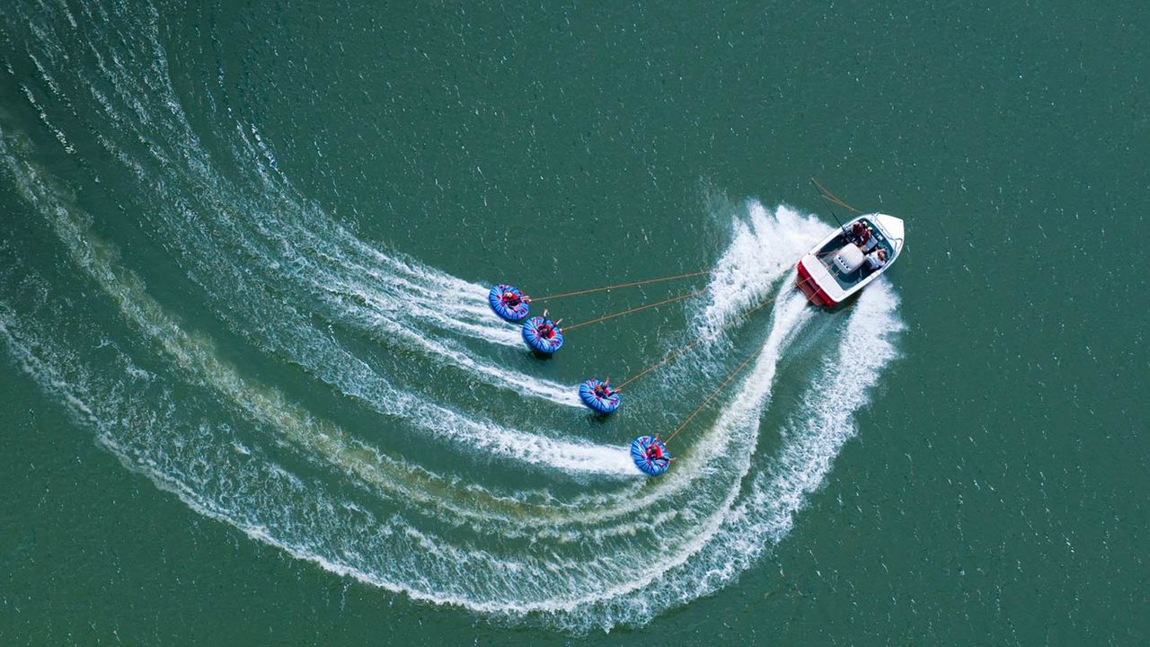 A speedboat tows four “tubers” on Abbey Lake in Surrey, England