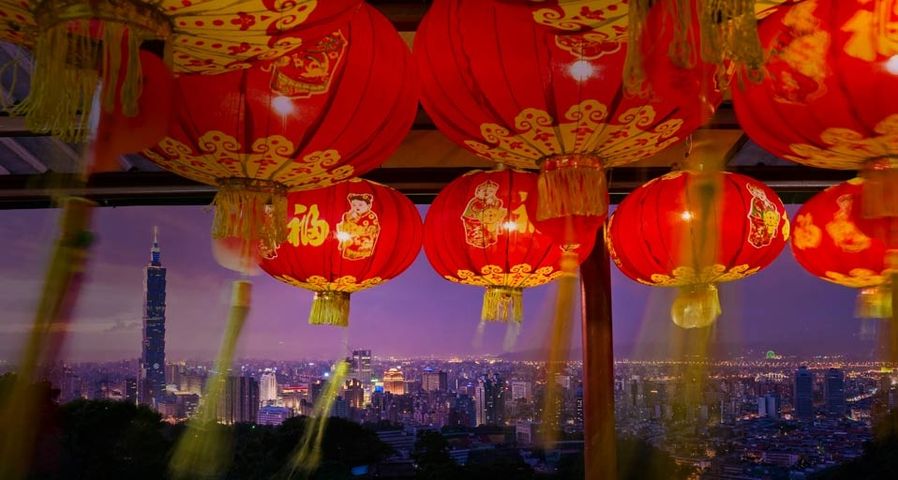 从挂满灯笼的寺庙看向远处的台北101
