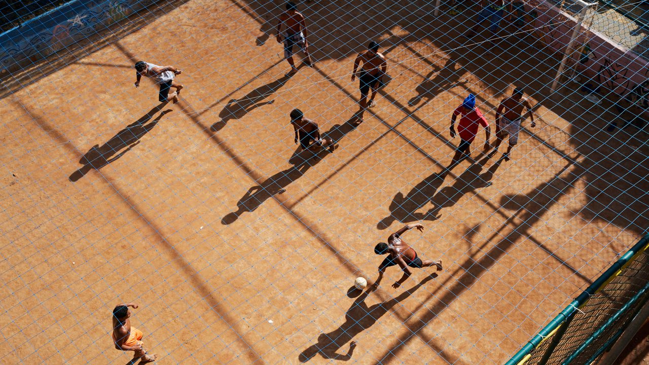 Vista aérea de jovens jogando futebol em um campo de terra em uma comunidade do Rio de Janeiro, RJ