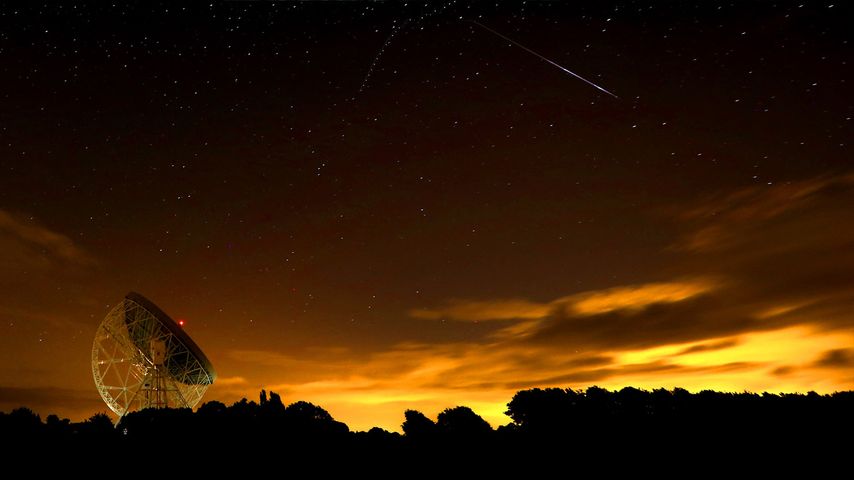 A Perseid meteor streaks across the sky over the Lovell Radio Telescope at Jodrell Bank