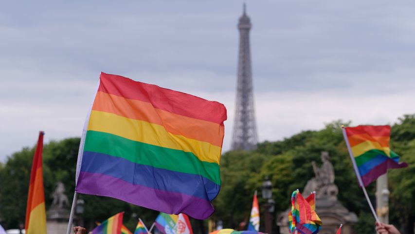 Drapeau arc-en-ciel brandi devant la tour Eiffel lors de la marche des fiertés