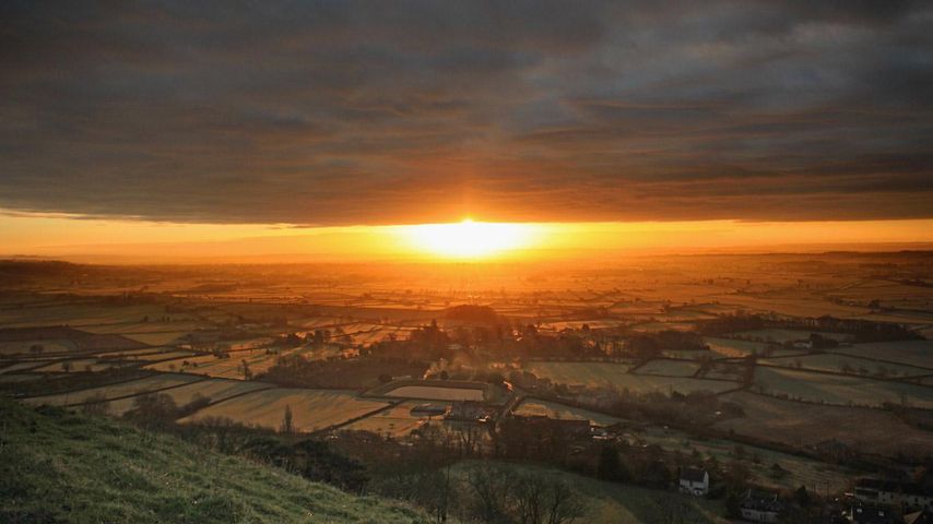 The sun rises over the Somerset Levels viewed from Glastonbury Tor in Glastonbury, England