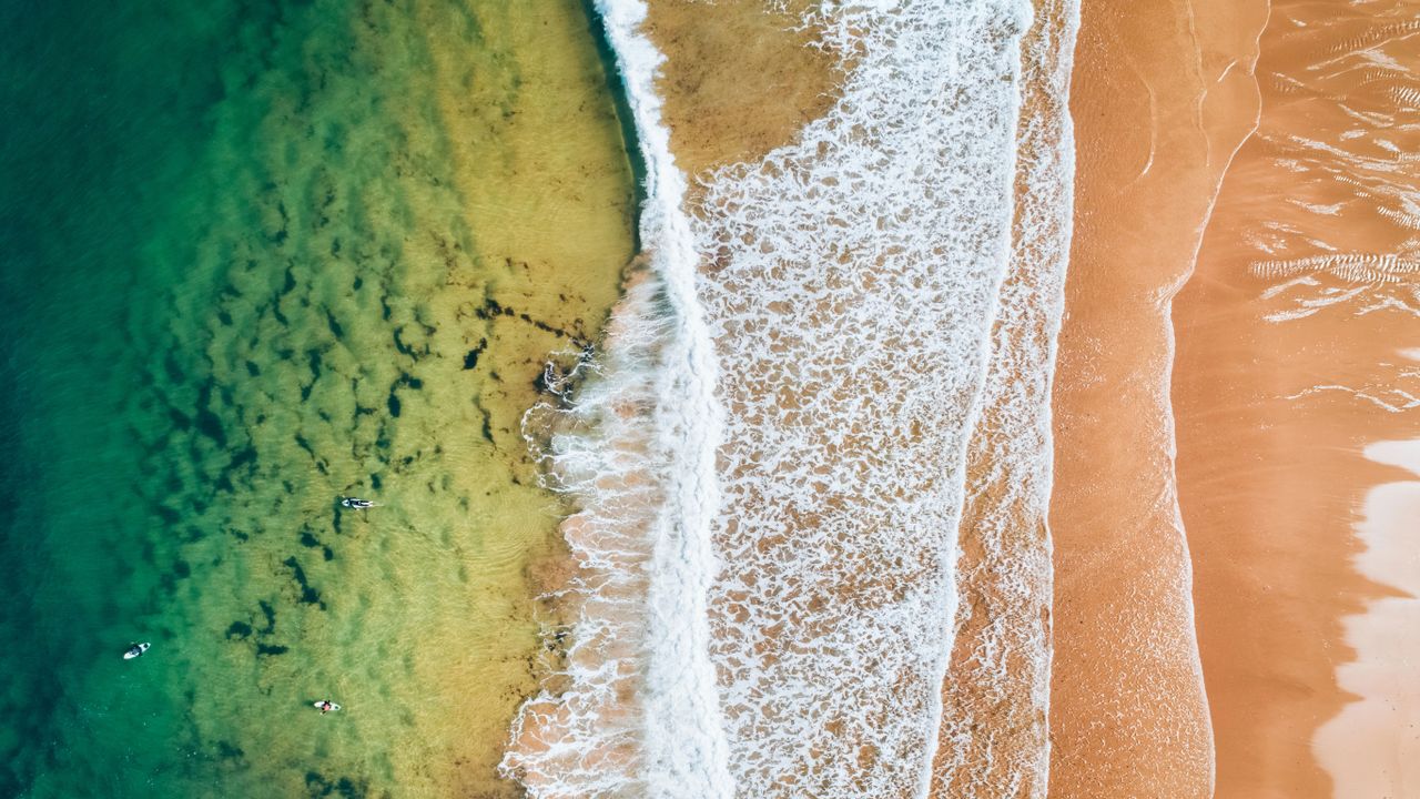 Vista aérea de surfista en el agua en una playa en Asturias, España