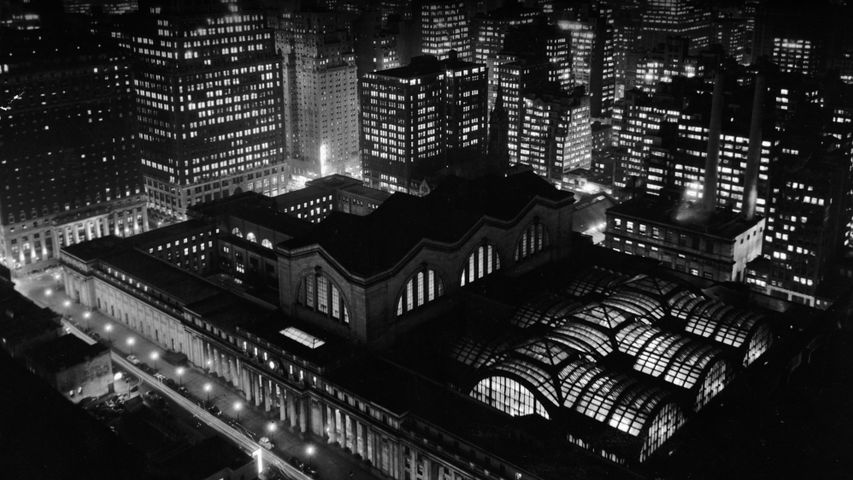Aerial view of Penn Station and the New York City skyline at night in the 1950s