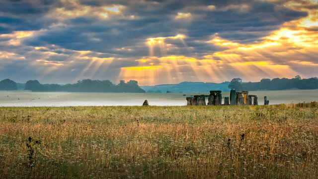 Cloudy sunrise over Stonehenge - prehistoric megalith monument arranged in circle.
