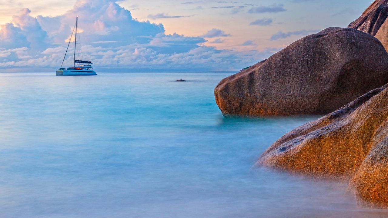 Granite coastal boulders and sailboat on Indian Ocean, Praslin, Seychelles