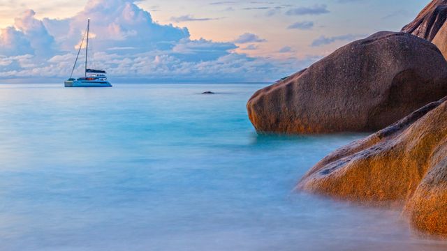 Granite coastal boulders and sailboat on Indian Ocean, Praslin, Seychelles