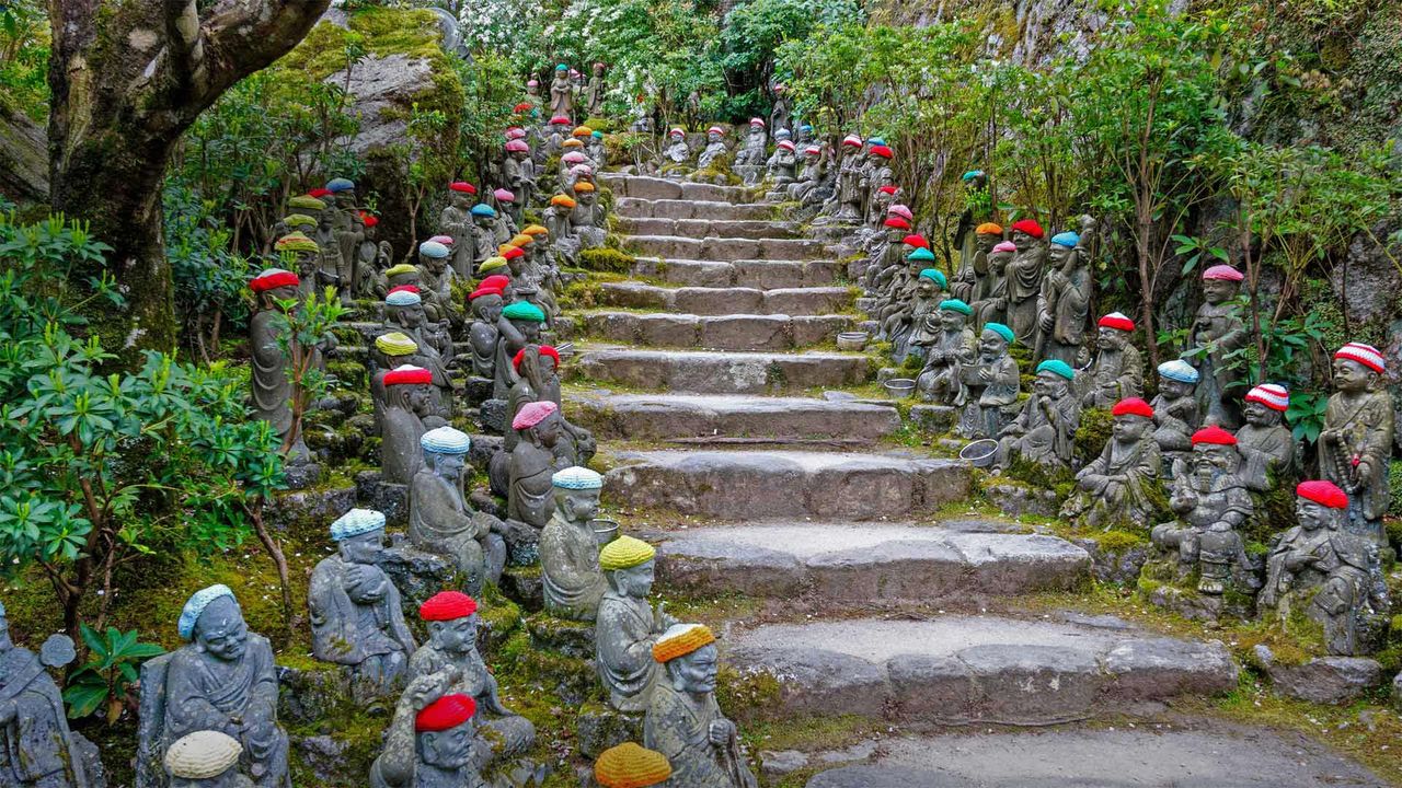 Figuras rakan en el camino de piedra que conduce al templo Daisho-in, Miyajima, Japón