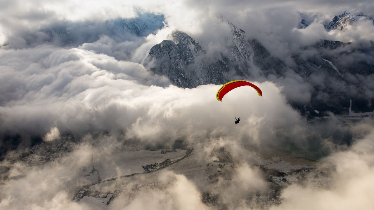 Red yellow paraglider, snow mountains, clouds