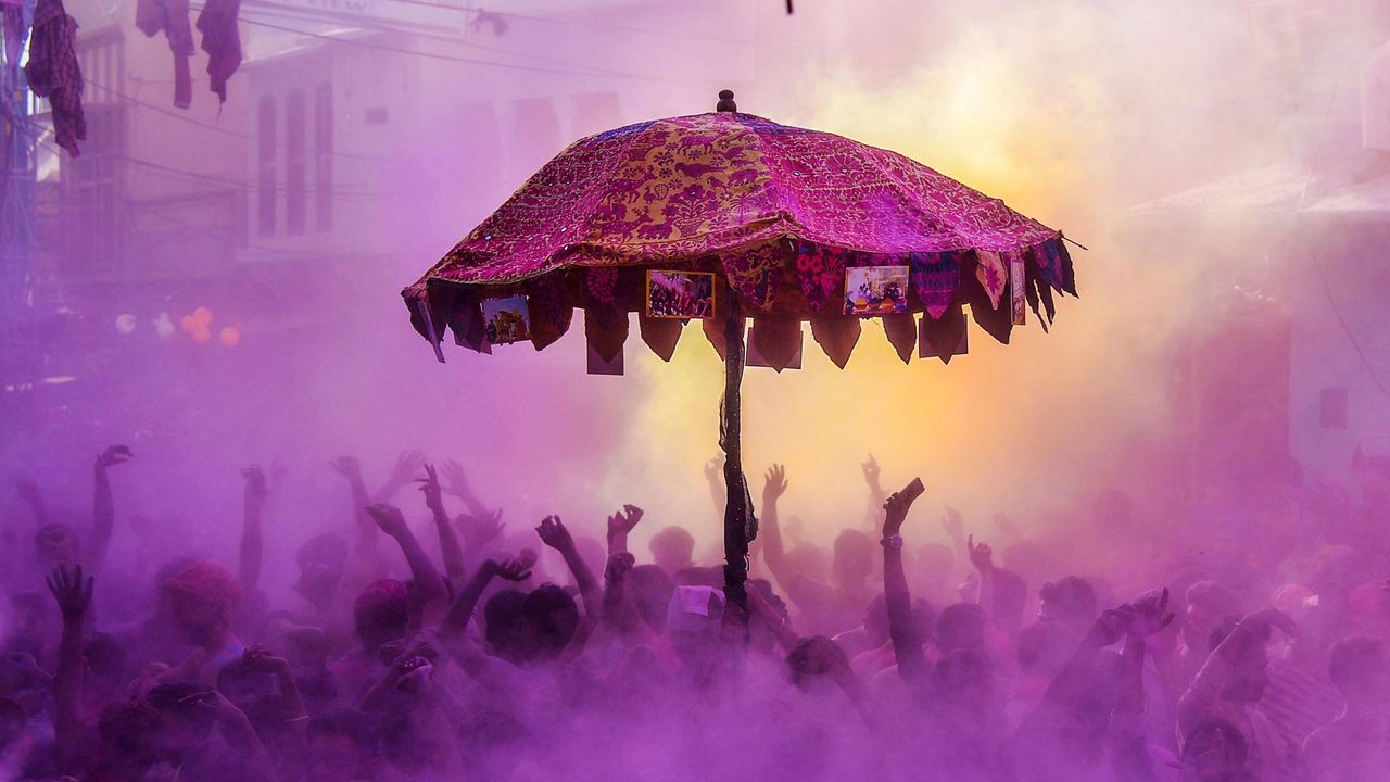 Devotees and foreign tourists partaking in 'kapda-phaar' during Holi celebrations.